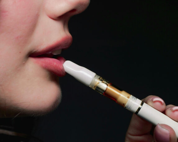 Close-up of a woman using a THC vape cartridge, illustrating how vape carts are commonly used for medical cannabis consumption in the UK.