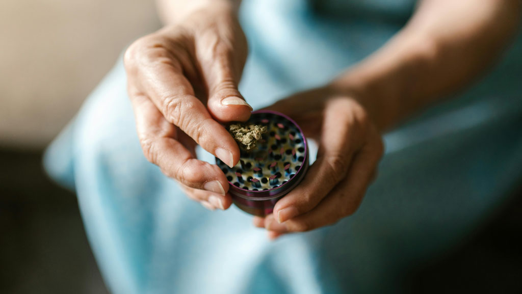 Woman grinding medical cannabis flower before using a dry herb vaporiser – part of the preparation process for safely and effectively using a dry herb vaporiser in the UK.
