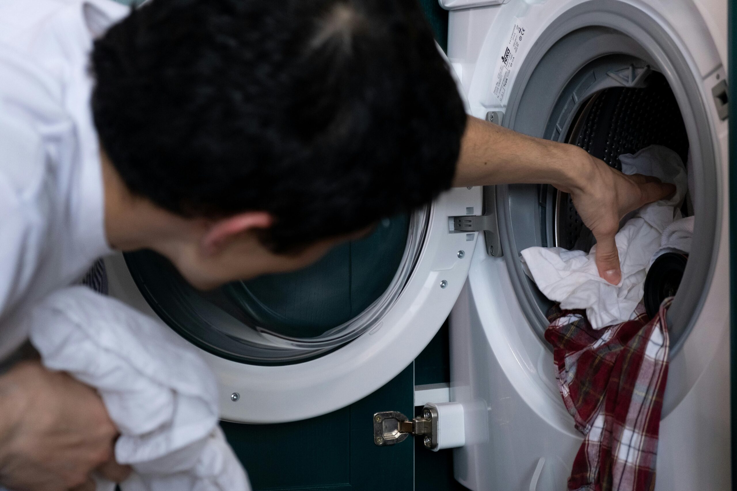 Man doing laundry to remove lingering cannabis smell from clothes after medical use.