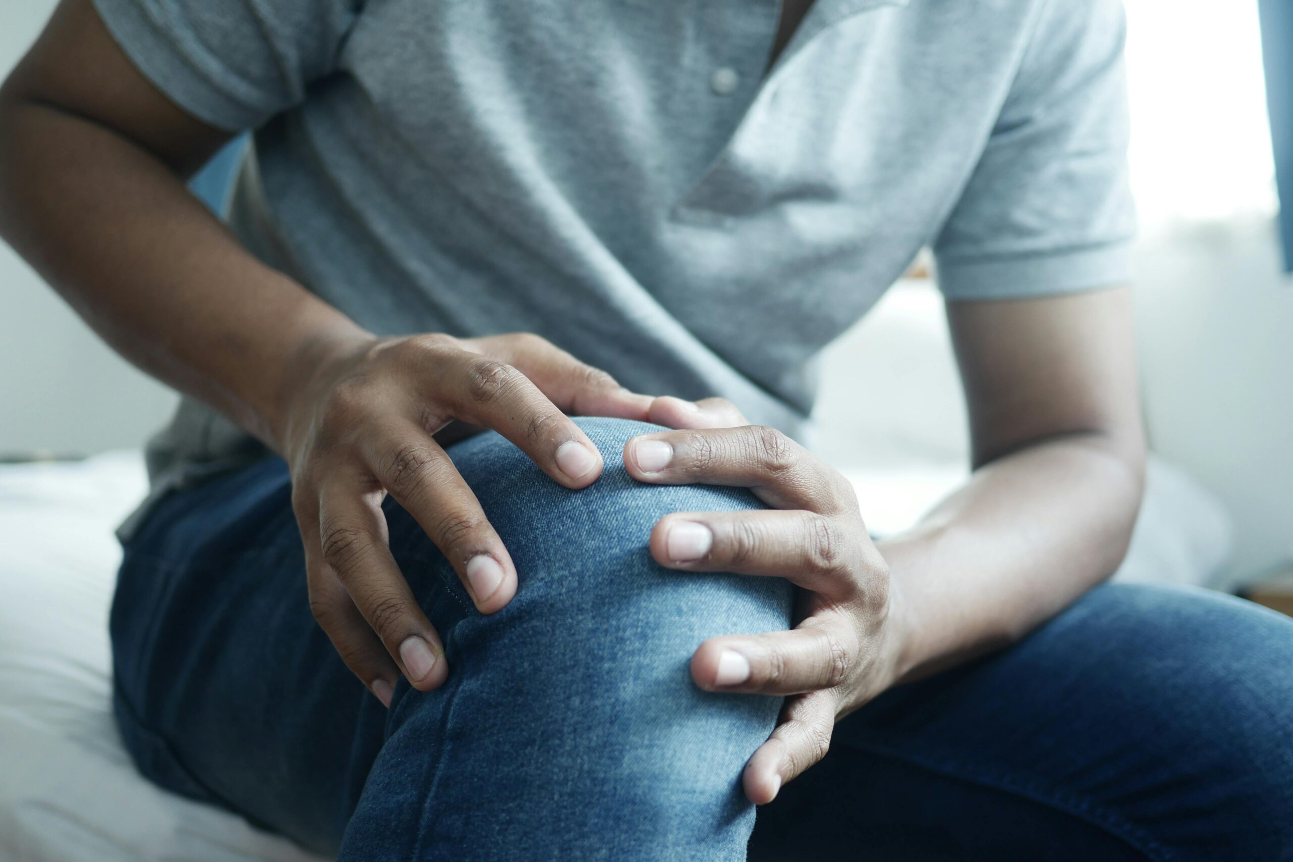 Person holding knee in pain, representing osteoarthritis relief through medical cannabis treatment