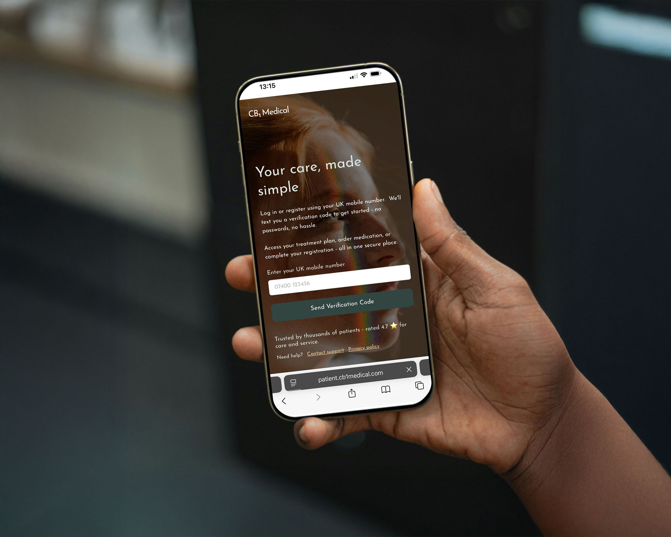 A hand is holding a mobile phone with the CB1 Patient Platform log in page on screen.