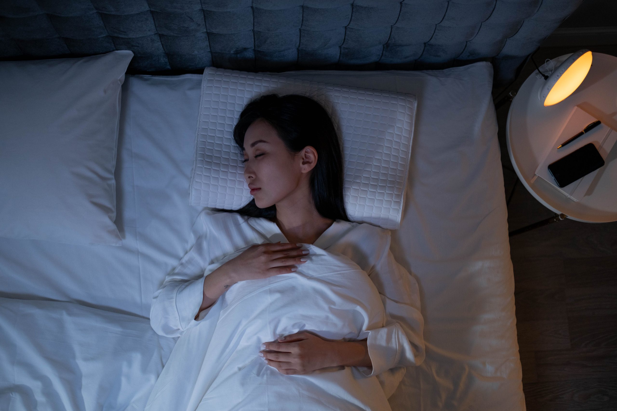 Woman sleeping peacefully in bed, illustrating how to get more deep sleep
